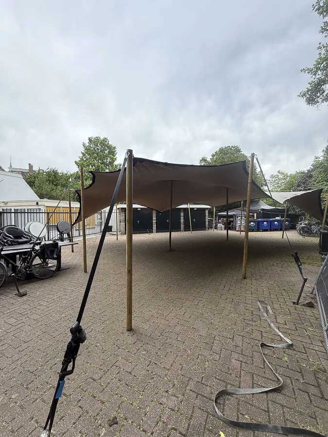 Stretchtent wordt opgespannen op een bestrating