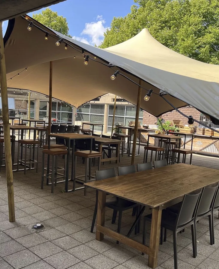 Terras met lange tafels onder een stretchtent
